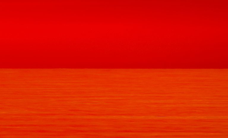 Aufnahme mit Teleobjektiv. In den orange Flächen sind die Wellen höher und stiler. Sie spiegeln auch höhere Teile des Himmels.